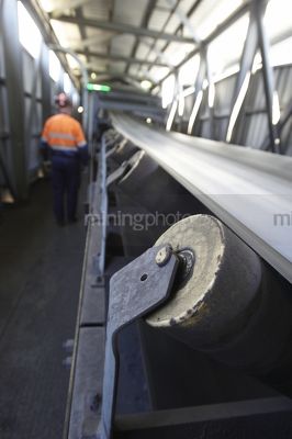 Mine worker in background walking alongside coal conveyor - Mining Photo Stock Library