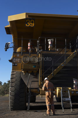 Maintenance worker servicing haul truck.  close up from the front of the machine. - Mining Photo Stock Library