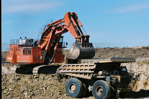 Large digger loading overburden into haul truck in an opencut mine - Mining Photo Stock Library