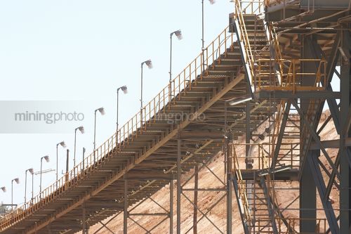 Conveyor at gold mine plant with stockpile in background. - Mining Photo Stock Library