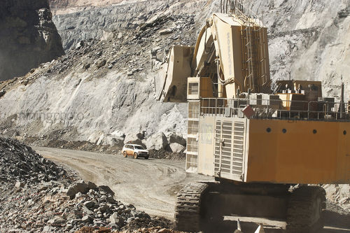 Large shovel excavator walking along haul road with light vehicle in background. - Mining Photo Stock Library