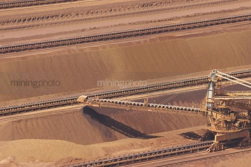 Close up aerial shot of iron ore reclaimer working at shipping terminal.  this shot shows the scale of the machinery. - Mining Photo Stock Library