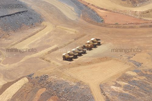 6 six trucks and water cart parked up at the go line on open cut mine site.  aerial shot. - Mining Photo Stock Library