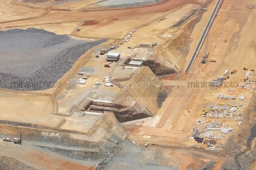 Great aerial photo of iron ore mine under construction. the conveyor and hopper are being built and in the foreground the drill rig is ready for blasting. - Mining Photo Stock Library