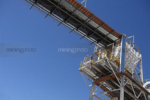 Overhead electrical tracks and conveyor into a hopper on a coal mine. - Mining Photo Stock Library