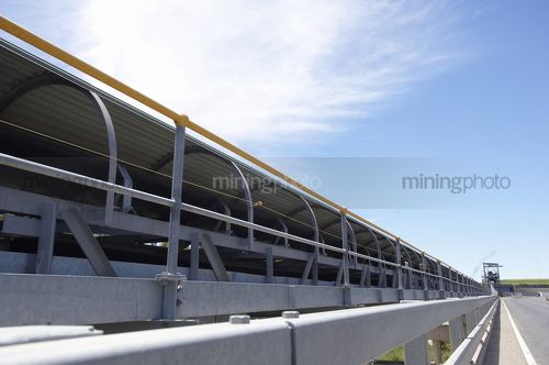 Covered coal conveyor on concrete bridge from dump Hopper in background.  safety pull stop visible - Mining Photo Stock Library