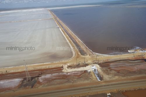 Aerial shot of large salt lakes, some still with water.  rail line in foreground - Mining Photo Stock Library