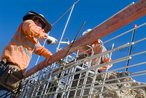 Construction worker outside in full PPE tying formwork for concrete together - Mining Photo Stock Library