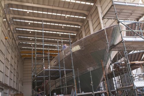 Boat hull under construction inside a factory. - Mining Photo Stock Library