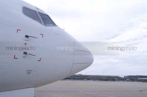 Nose of 747 aeroplane shot close up at airport with rail transport in background. - Mining Photo Stock Library