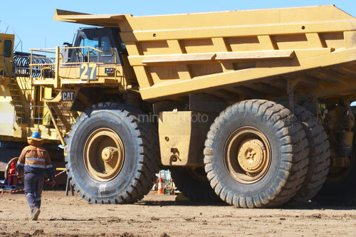 Mine worker in full PPE walks to parked up haul truck. - Mining Photo Stock Library