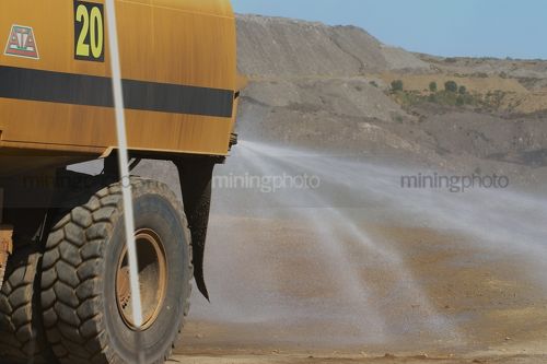 Close up of water truck spraying water for dust suppression on haul road at open cut mine. - Mining Photo Stock Library