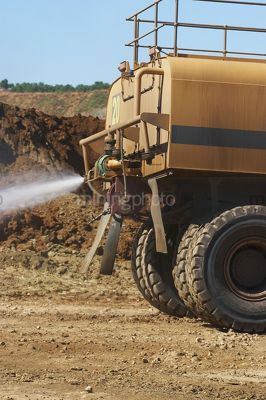 Close up of water cart sprying watewr on haul road for dust suppression. - Mining Photo Stock Library