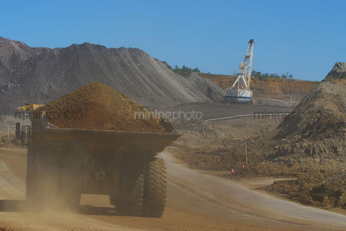 Loaded haul truck from open cut mine travels on haul road past drag line. - Mining Photo Stock Library