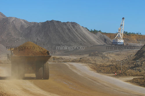 Loaded haul truck from open cut mine travels on haul road past drag line. - Mining Photo Stock Library