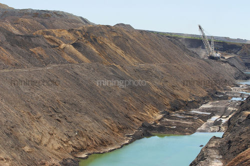 Drgaline moving overburden in open cut mine. stockpiled earth in foreground. - Mining Photo Stock Library