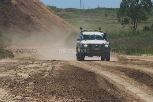 Mine ready light vehicle moving on mine access road.  focus is on road in foreground. lots of space on photo for copy. - Mining Photo Stock Library