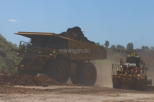 Loaded haul truck with overburden moving on haul road with grader working in foreground. - Mining Photo Stock Library