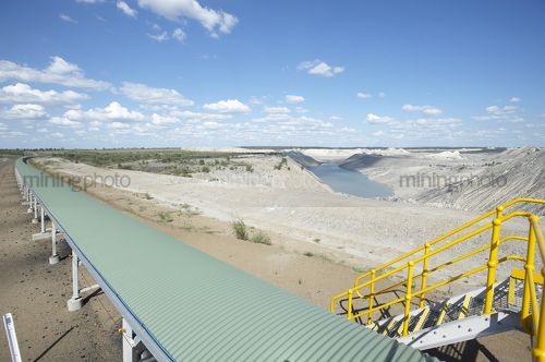 Covered, overland, coal conveyor with mine workings in background and pedestrian overpass in foreground. - Mining Photo Stock Library