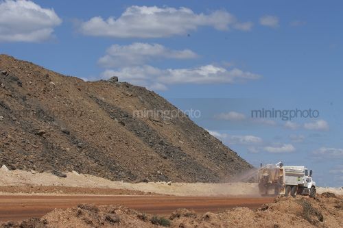 Water cart spraying for dust suppression on haul road at open cut coal mine.  overburden stockpiled in background. - Mining Photo Stock Library