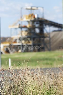 Great generic shot of coal wash plant  at open cut mine.  grass plants in foreground in focus with green grass in middle ground. - Mining Photo Stock Library