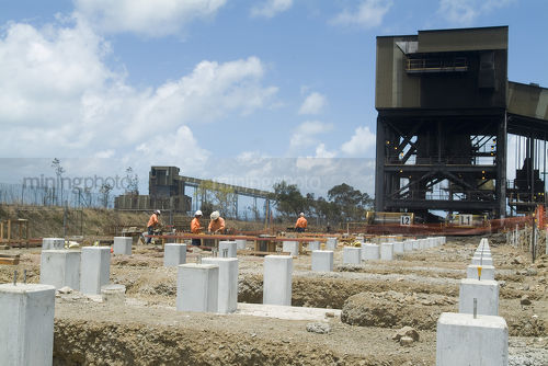 Construction of coal terminal port expansion. male workers in PPE with pre cast concrete pillars - Mining Photo Stock Library