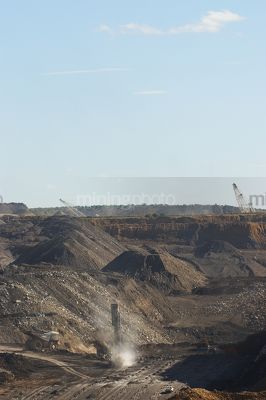 Wide open cut mine shot showing haul truck, drill drilling blast holes, excavators and two draglines.  vertical shot. - Mining Photo Stock Library