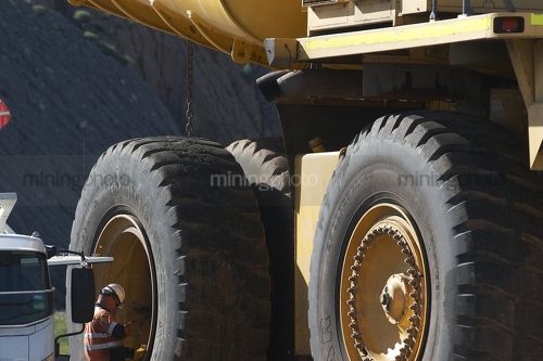 Tyre fitter mine worker inspecting haul truck tyre.  great scale. - Mining Photo Stock Library