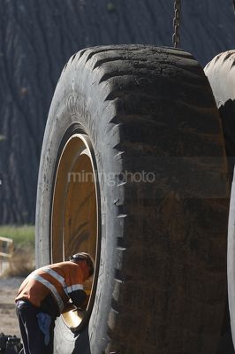 Tyre fitter mine worker inspecting haul truck tyre.  great scale. - Mining Photo Stock Library