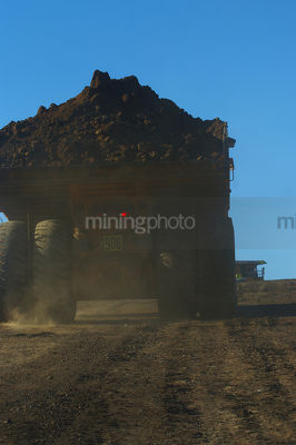 Back of loaded haul truck on haul road with deep blue sky behind. - Mining Photo Stock Library