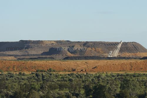 Wide mine shot showing stockpiled overburden and top of dragline. rehabilitation and revegetation in foreground. - Mining Photo Stock Library