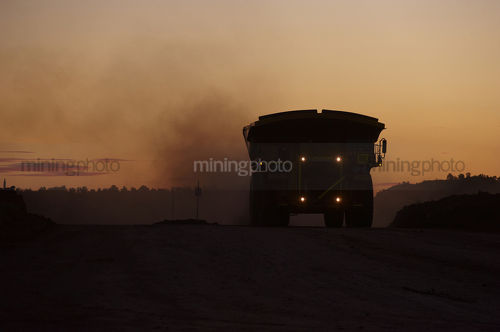 Dusk shot of loaded haul trucks on haul road in open cut mine. - Mining Photo Stock Library