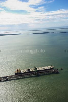 Vertical aerial shot of coal ship being loaded at wharf.  lots of islands in background - Mining Photo Stock Library