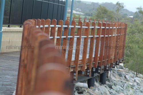 Pedestrian board walk timber railing curving around. foundation pilons into rock retaining wall - Mining Photo Stock Library