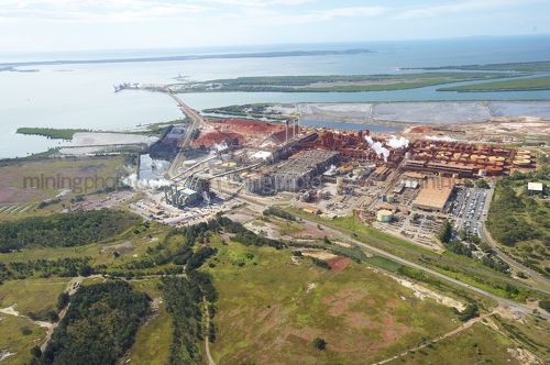 Wide aerial photo of a bauxite alumina refinery.  clearly depicts wharf shipping and all areas of processing plant. - Mining Photo Stock Library