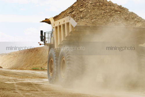 Close up photo of a loaded haul truck moving in open cut mine - Mining Photo Stock Library