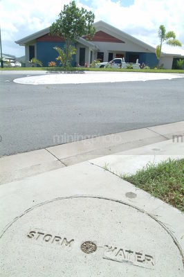 Storm water pipe cover next to road in residential property subdivsion.  vertical shot. - Mining Photo Stock Library