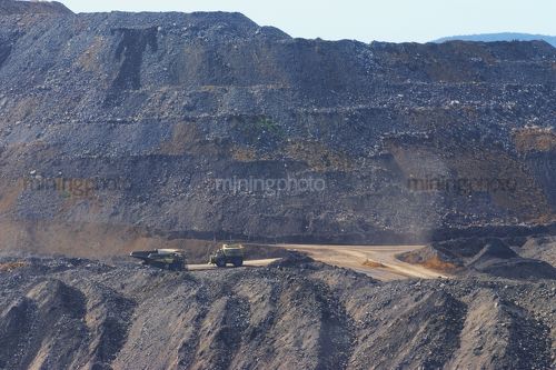 Water cart and haul truck pass on mine site haul road.
wide photo with over burden stockpiles in background. - Mining Photo Stock Library