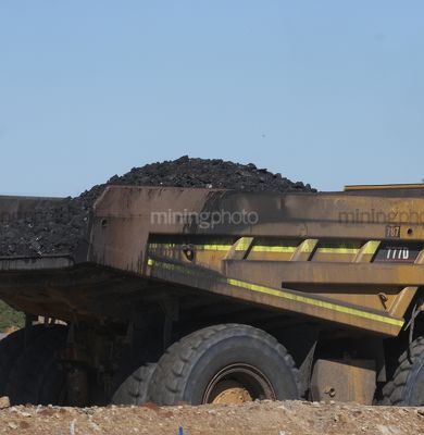 Close up photo of loaded coal haul truck moving on haul road at open cut mine site. - Mining Photo Stock Library