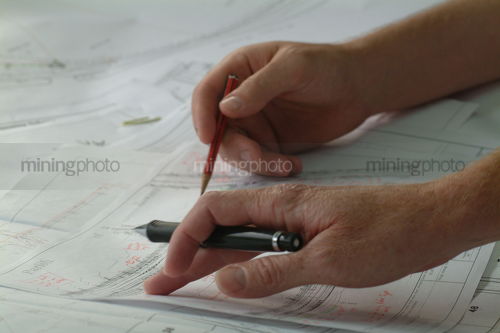 Closeup of hands with pen and pencil above engineering plans. good generic shot - Mining Photo Stock Library