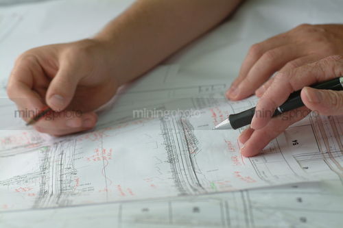 Closeup of hands with pen and pencil above engineering plans. good generic shot - Mining Photo Stock Library