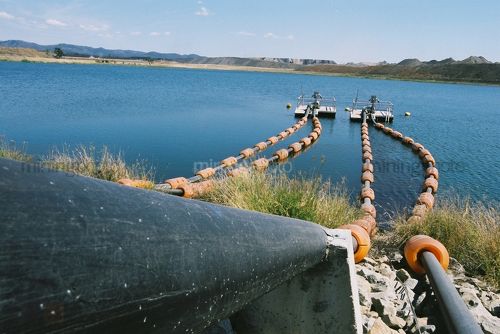 Water float pumps in a coal mine dam.  overburden stockpiles in thre background. - Mining Photo Stock Library