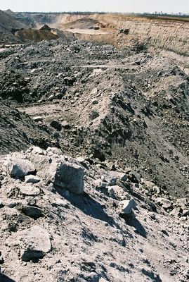 Vertical photo of open cut coal mining.  foreground of overburden stockpile in focus, heavy equipment in background out of focus.  great eneric shot. - Mining Photo Stock Library