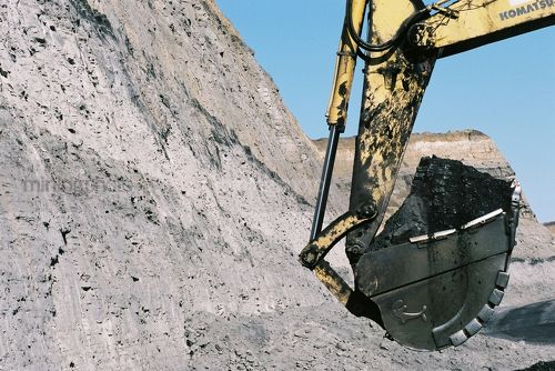 Close up of excavator bucket loaded with coal in open cut coal mine.  coal seam in high wall behind in background. - Mining Photo Stock Library