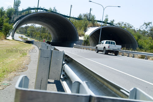 Light vehicle car driving on road through bebo archway bridge. guide rails and established koala crossing adjacent - Mining Photo Stock Library