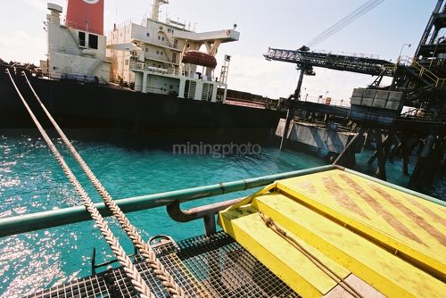 Shiploaer loading coal at a terminal with ship in background, shot from wharf - Mining Photo Stock Library