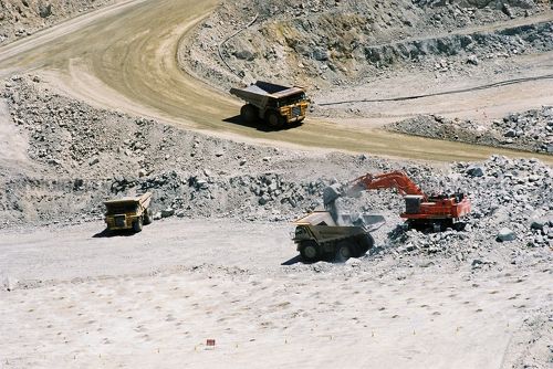 Photo of truck rotation at open cut gold mine.  blast drill holes in foreground. - Mining Photo Stock Library
