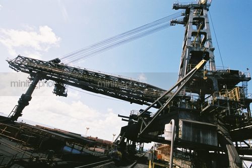 Close up photo of shiploader loading coal into a ship at coal terminal.  - Mining Photo Stock Library