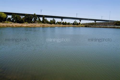 Looking across large dam to aerial rail bridge flyover.   - Mining Photo Stock Library