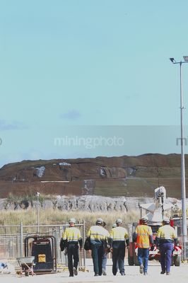 Five workers in mine site walking to their task.  vertical image. - Mining Photo Stock Library